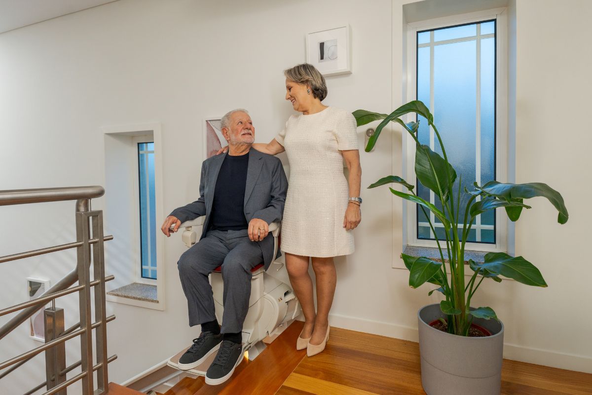 Casal feliz em casa, com uma cadeira elevatória Stannah